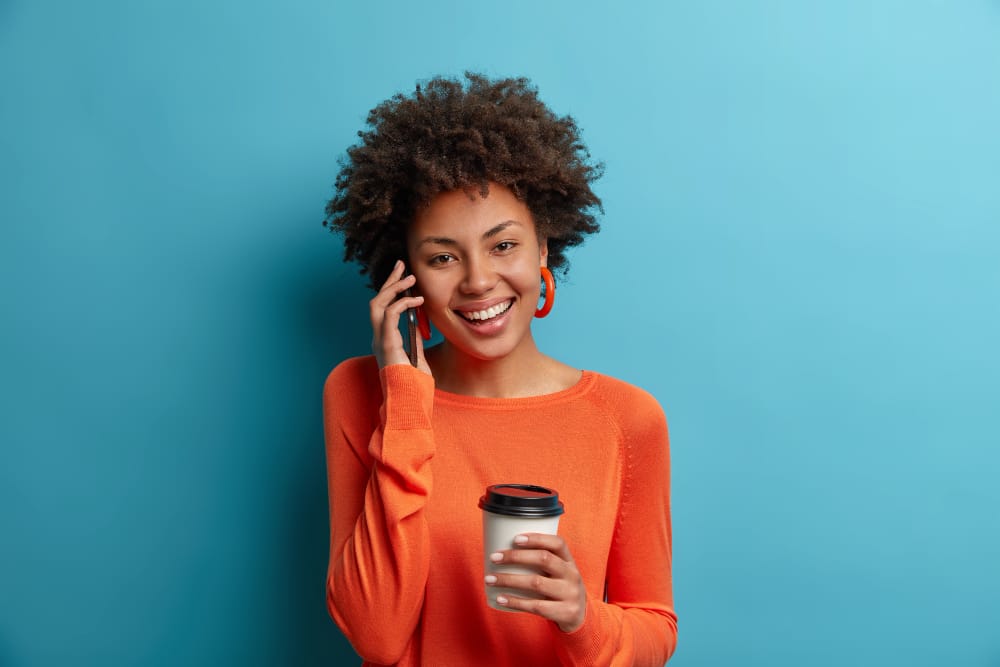jeune femme au téléphone tenant un mug dans ses mains