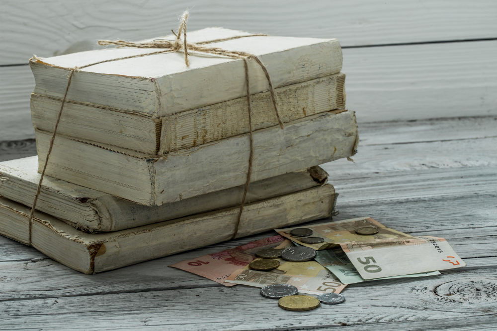 pile de livres anciens et billets et pièces de monnaie posés à coté