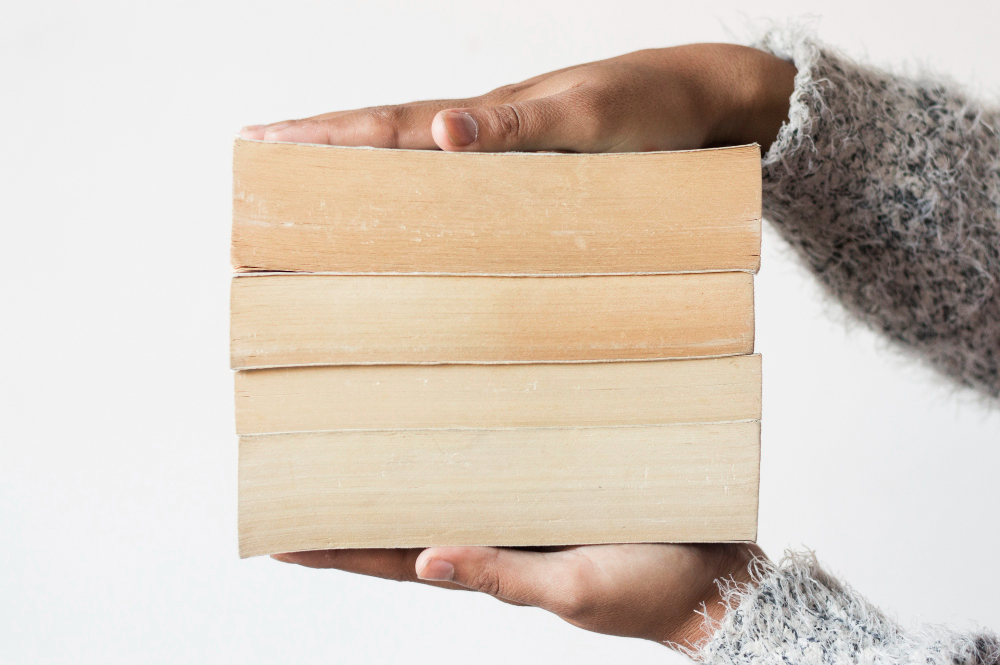 Homme tenant 3 livres (3 tomes d'une série) entre ses mains