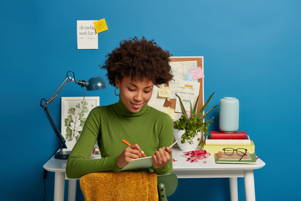 Femme écrivant sur un carnet assise à son bureau